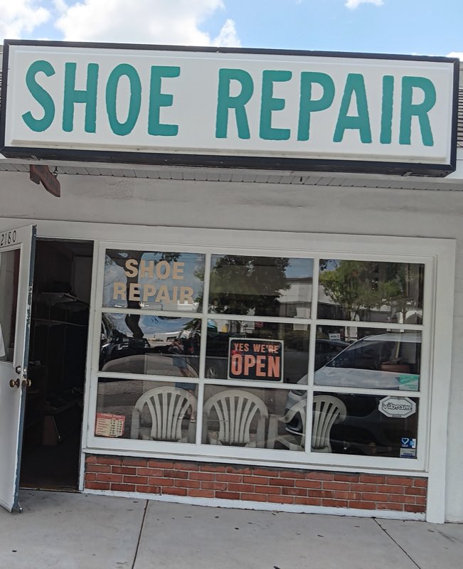 Gulf Gate Shoe Repair storefront with a hand-painted teal SHOE REPAIR sign and a Yes We're Open sign